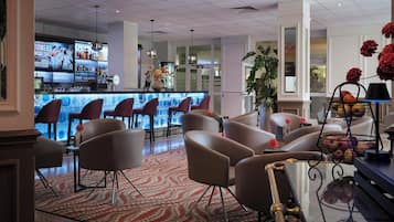 Eine Hotelhalle mit Barbereich, Sitzgelegenheiten und Dekorationselementen.