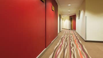Un corridoio d'albergo con pareti rosse e una moquette fantasia.