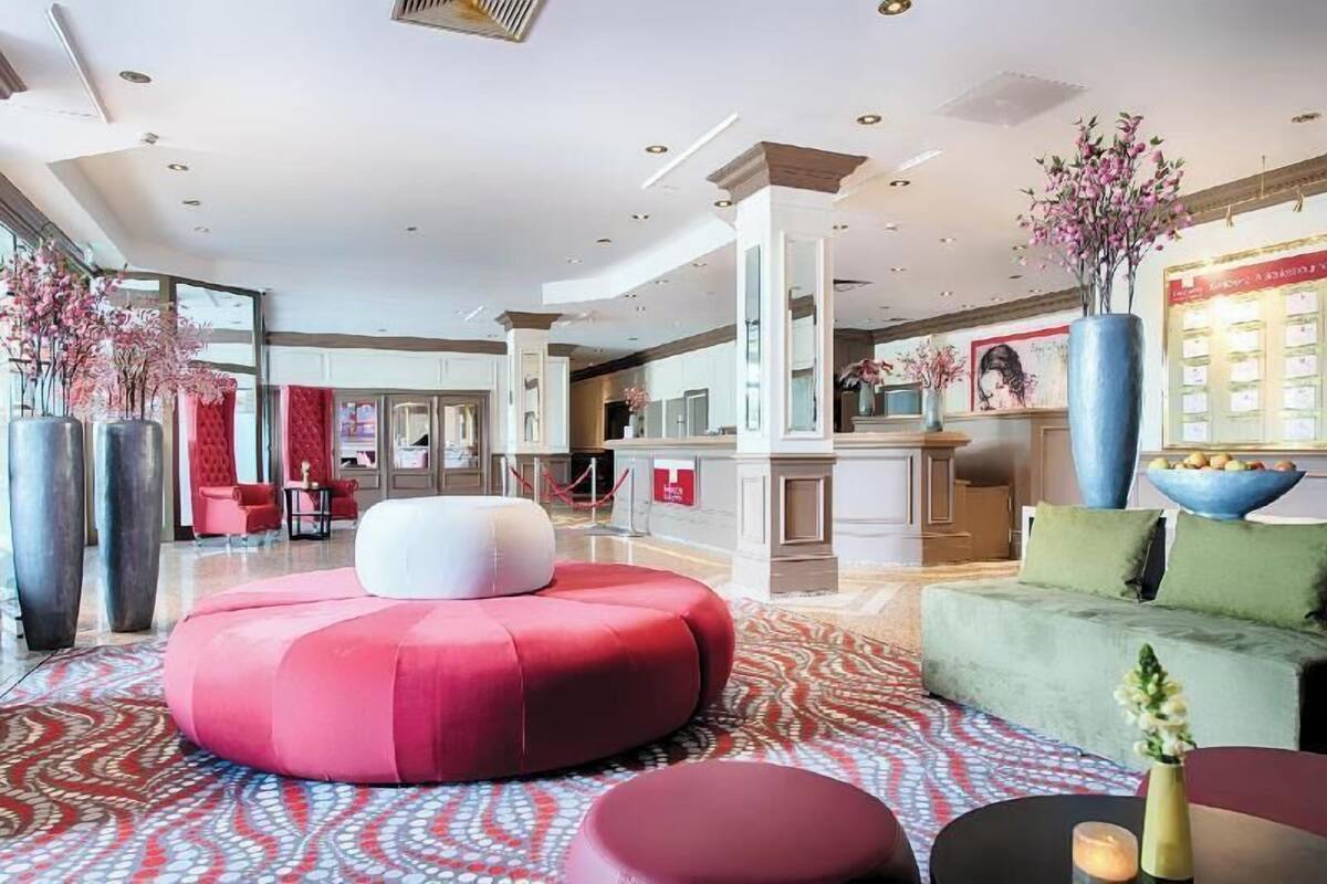 Eine moderne Lobby mit einer zentralen Sitzecke, einem Empfangstresen und einem großen Fenster.