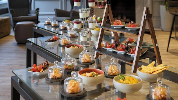 Une table de buffet proposant divers plats et un présentoir à bouteilles dans un hôtel au décor moderne.