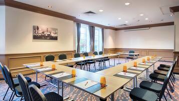A conference room with a long table, chairs, and a projector screen.