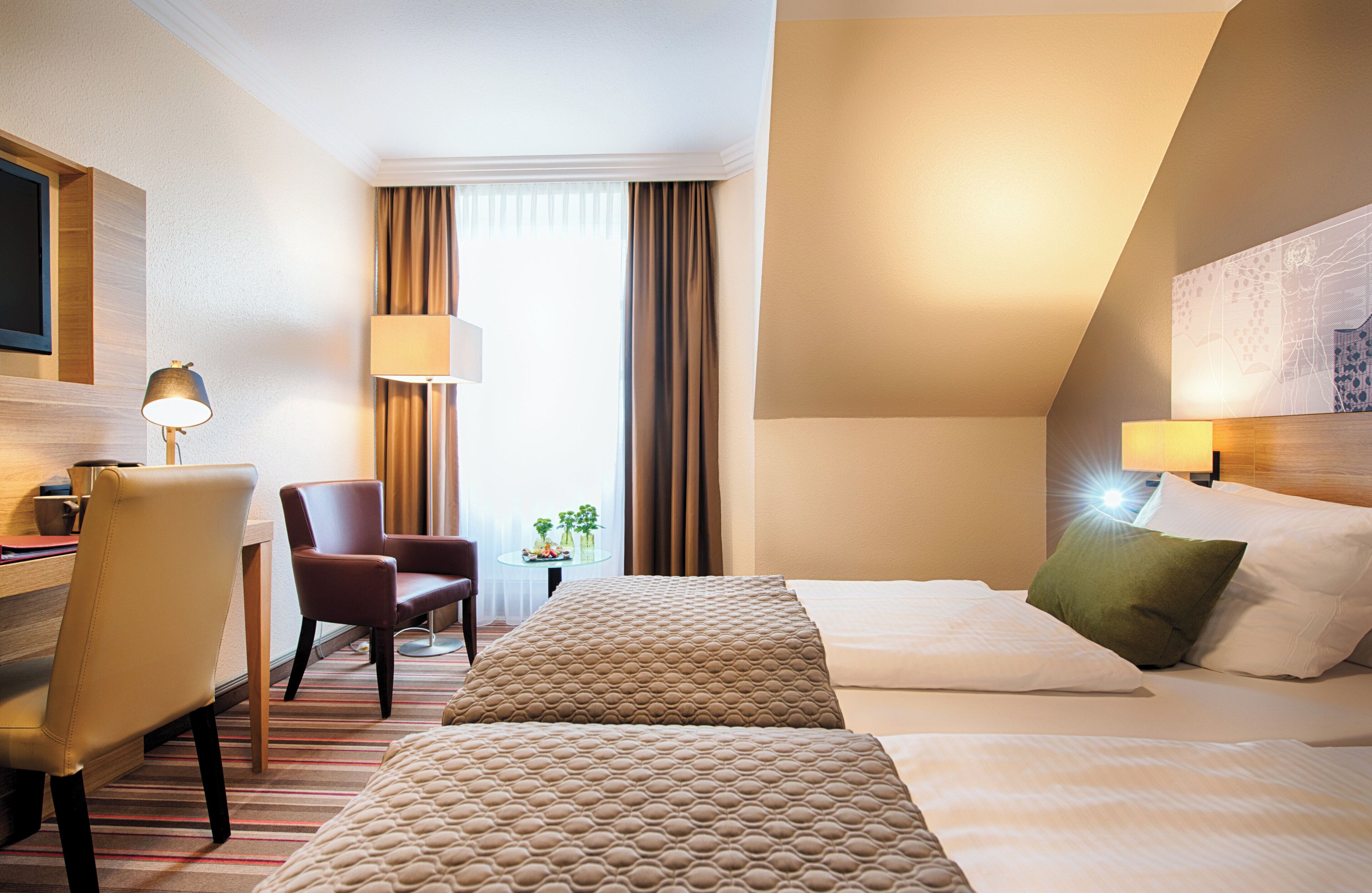 Habitación de hotel con dos camas, un escritorio, una silla, una lámpara y una ventana con cortinas.