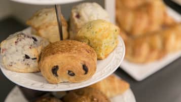 A multi-tiered display of assorted pastries, including croissants and scones, arranged on a white plate.