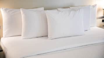 A neatly made bed with white bedding and pillows.