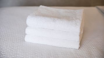 A stack of white towels on a textured white surface.