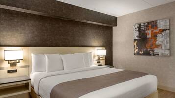 A hotel room with a large bed, bedside lamps, a nightstand, and a wall-mounted abstract painting.