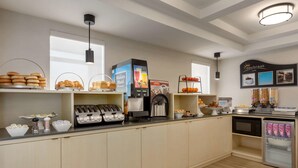 Una barra de desayuno con diferentes opciones de comida, una máquina de café y un microondas.