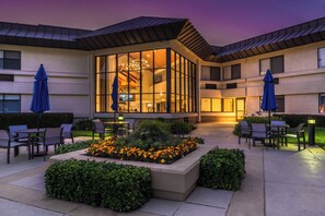 A hotel courtyard with outdoor seating, a glass-enclosed lounge, and a landscaped garden. - Holiday Inn Express Walnut Creek by IHG (Walnut Creek)