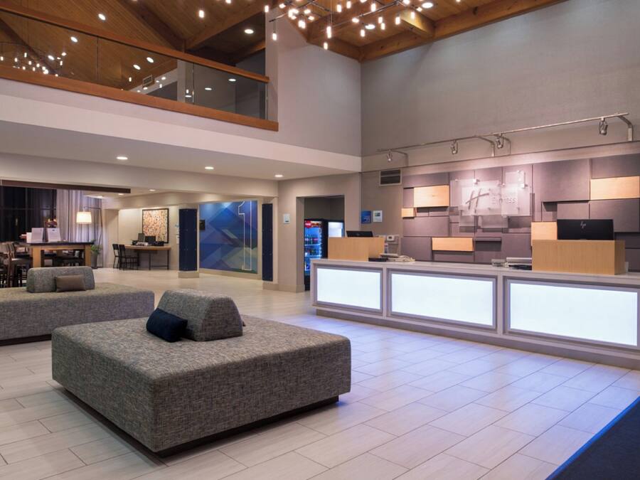 A spacious lobby with a reception desk, seating area, and a high ceiling with exposed beams.