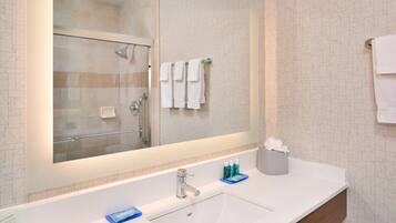 A bathroom with a large mirror, a sink, and a shower.
