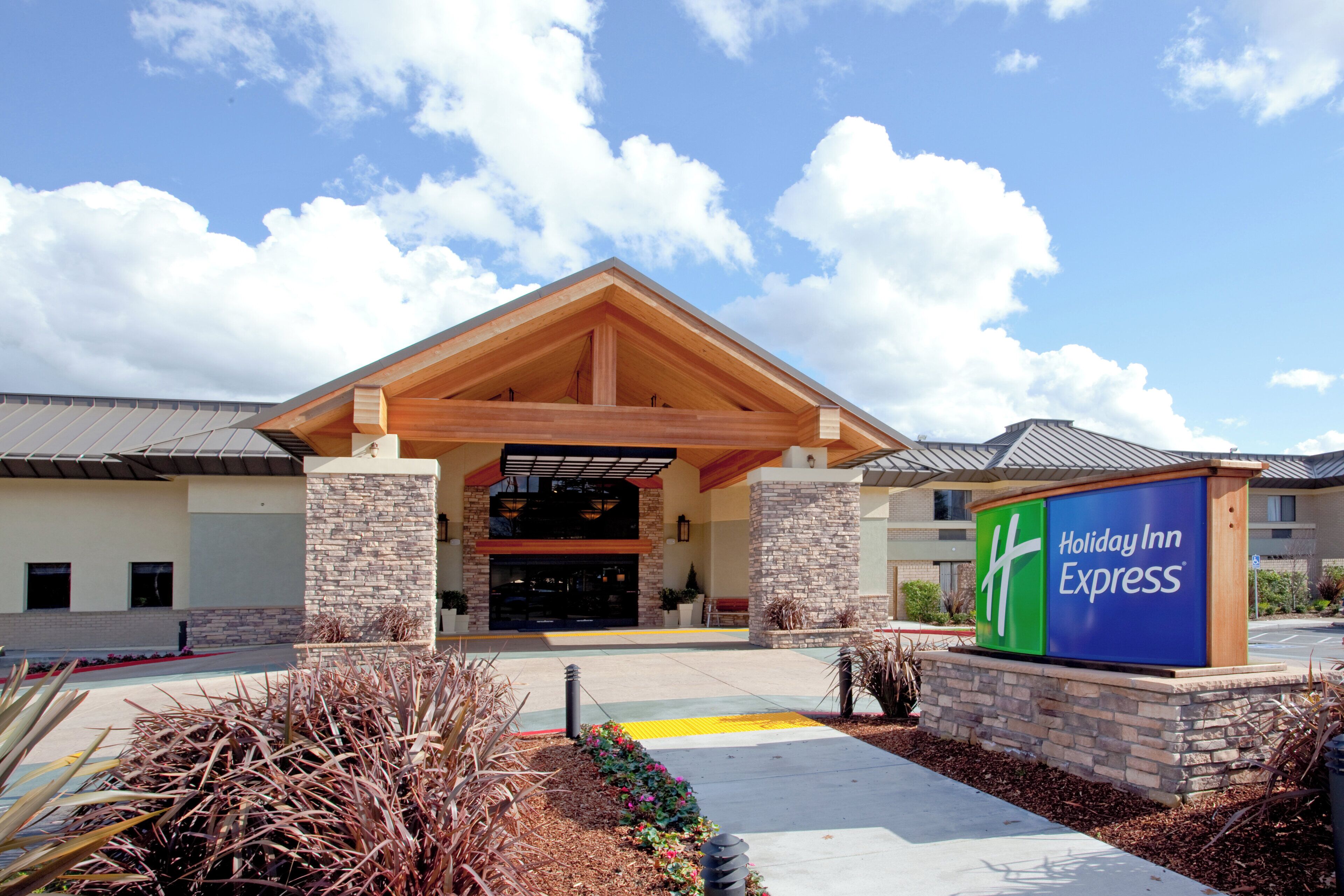 Un bâtiment de l’hôtel Holiday Inn Express avec une façade en pierre, une entrée couverte et une enseigne.