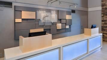 A modern reception desk with a flat-screen TV, a digital display, and a wooden accent.