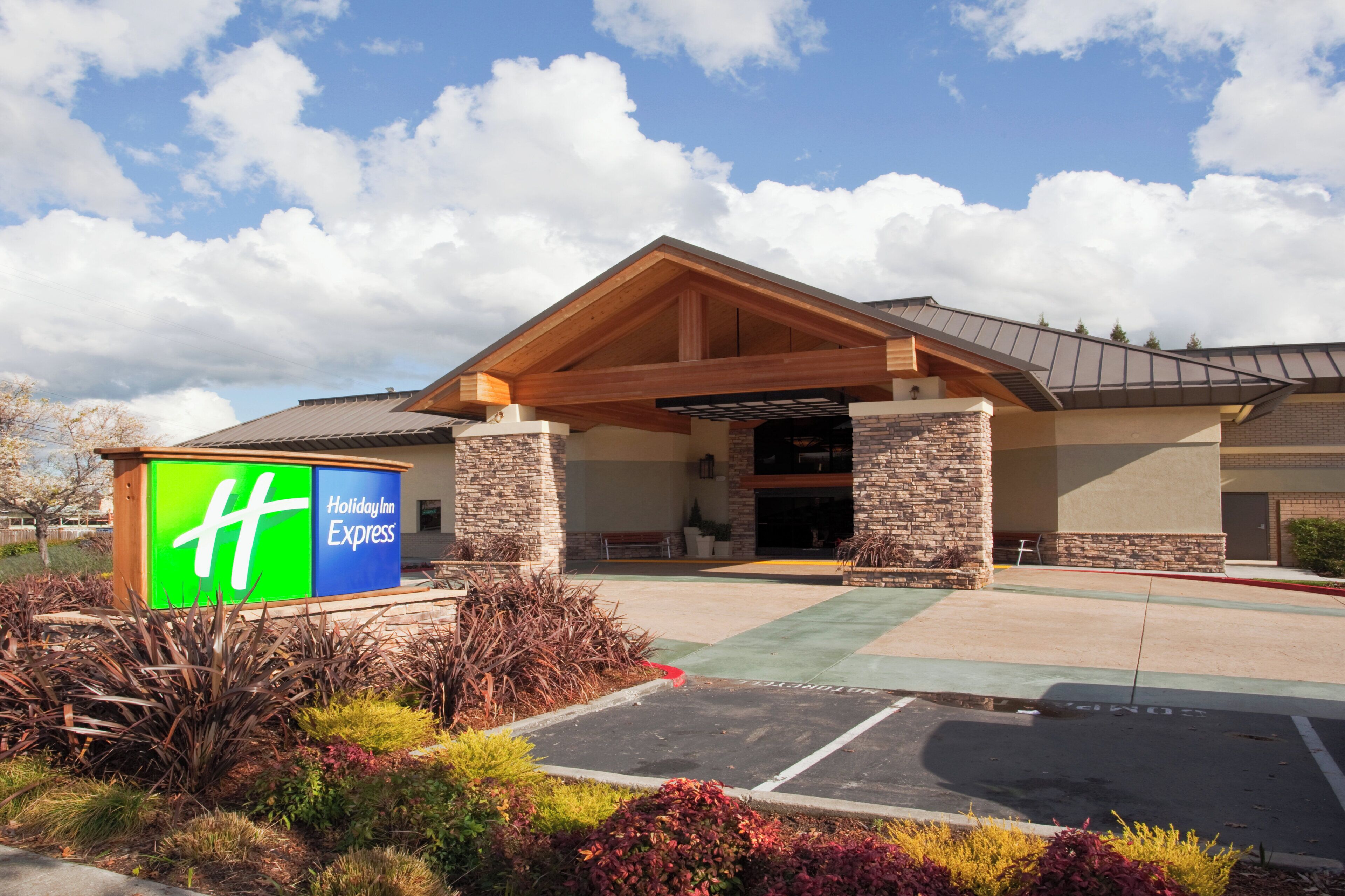 A Holiday Inn Express building with a stone facade, a covered entrance, and a parking lot.