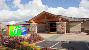 A Holiday Inn Express building with a stone facade, a covered entrance, and a parking lot.