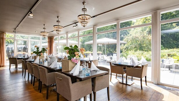 Un restaurant avec de grandes fenêtres, des tables et des chaises en bois.