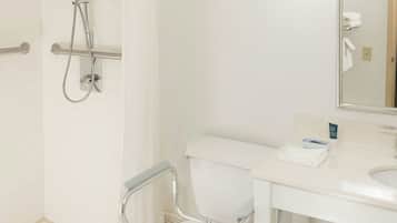 Un baño con inodoro blanco, lavabo, espejo y zona de ducha.