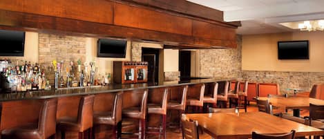 A bar area with a long counter, multiple seating options including booths and tables, and a stone accent wall.