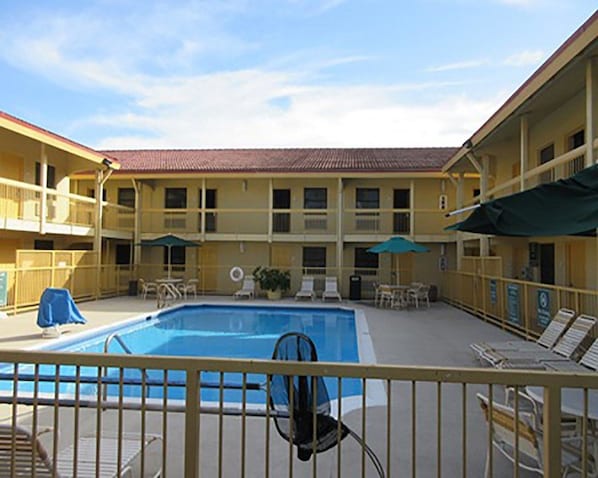 A hotel with a pool area, outdoor seating, and a two-story building with balconies.