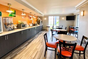 A modern restaurant with a kitchen counter, dining tables, and chairs.