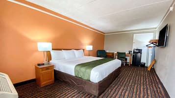 Habitación de hotel con una cama grande, dos mesitas de noche con lámparas, un escritorio con silla, televisión en la pared y suelo alfombrado.