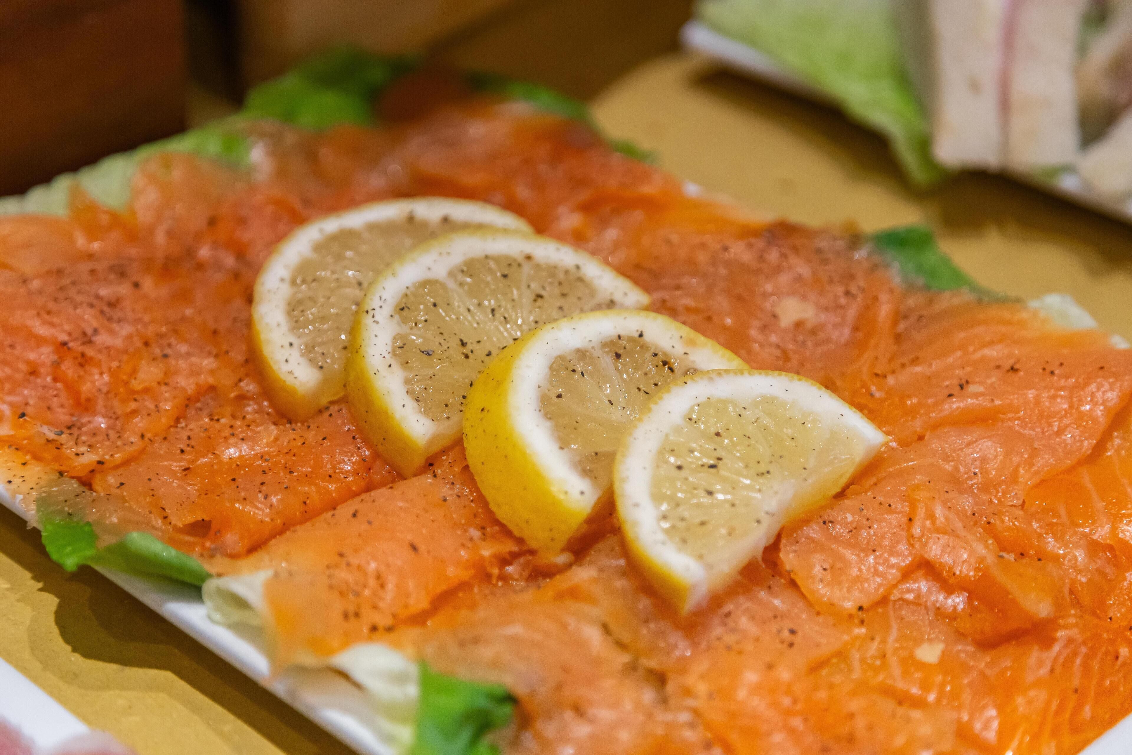 A plate of smoked salmon with lemon slices and herbs.