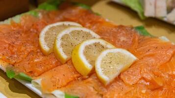 A plate of smoked salmon with lemon slices and herbs.
