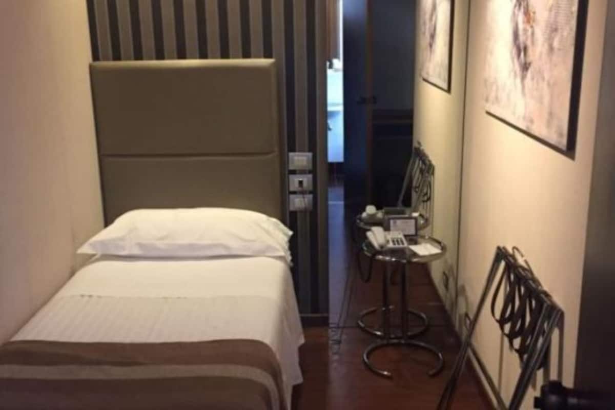 Habitación de hotel con una cama, una mesita con teléfono y una silla.