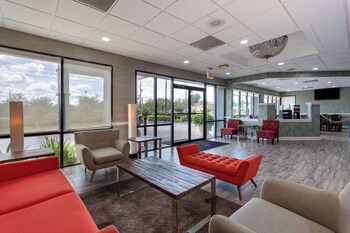 A restaurant with a long counter, wooden chairs, and a tiled floor. at Ramada by Wyndham Altamonte Springs Near I-4