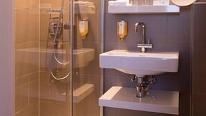 Une salle de bain moderne avec une douche à parois de verre, un lavabo blanc et un miroir au-dessus du lavabo.