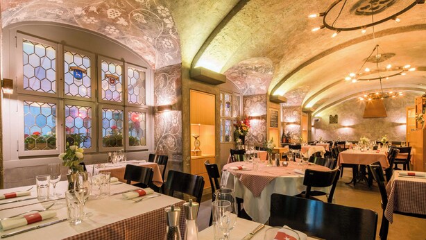 Un restaurant doté de vitraux hexagonaux, de tables recouvertes de nappes blanches et d’un intérieur chaleureux et rustique.