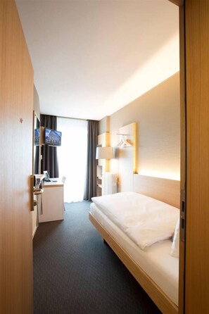 A hotel room with a bed, a desk, a TV, and a lamp. - Best Western Plus Hotel Zürcherhof (Zürich)