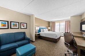 A hotel room with a bed, a desk, a chair, a sofa, and a television. - Comfort Suites Near Gettysburg Battlefield Visitor Center (Gettysburg)