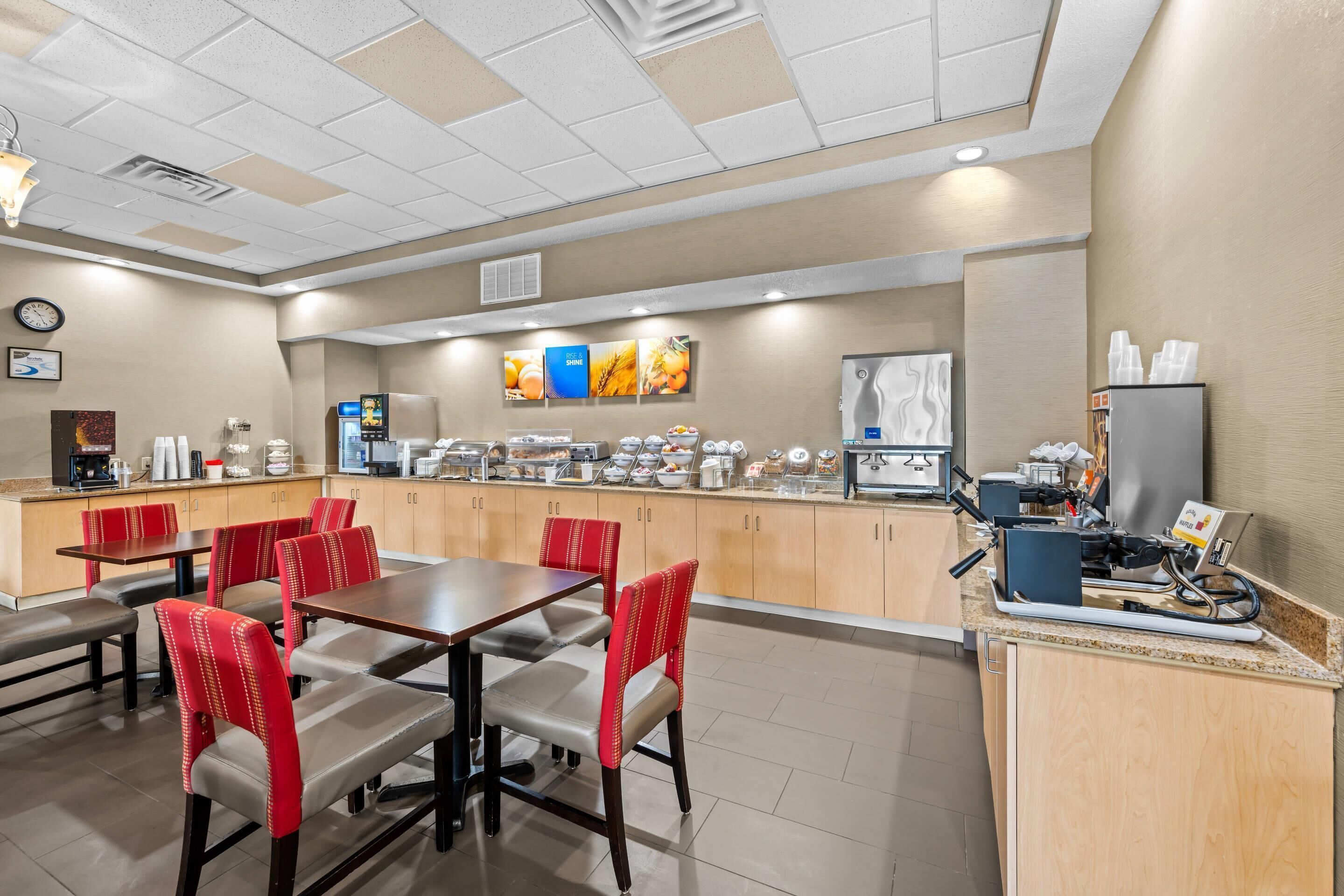 A hotel dining area with a buffet setup, seating arrangements, and a clock on the wall.