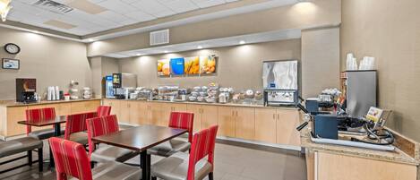 Un comedor de hotel con un sistema de buffet, mesas dispuestas y un reloj en la pared.