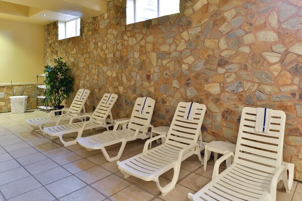A row of white sun loungers against a stone wall with a window above. - Comfort Suites Near Gettysburg Battlefield Visitor Center (Gettysburg)