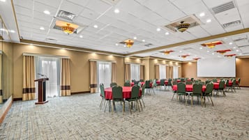 Una sala conferenze con vari tavoli e sedie, un podio e uno schermo di proiezione.