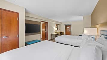 A hotel room with two beds, a desk, a chair, a television, and a door.