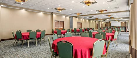 Une salle de conférence dotée de plusieurs tables et chaises, d’un revêtement de sol en moquette et d’un éclairage au plafond.