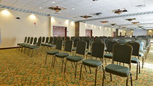 A conference room with rows of chairs and a patterned carpet.