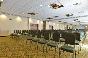 Un salón de conferencias con filas de sillas y una alfombra estampada.