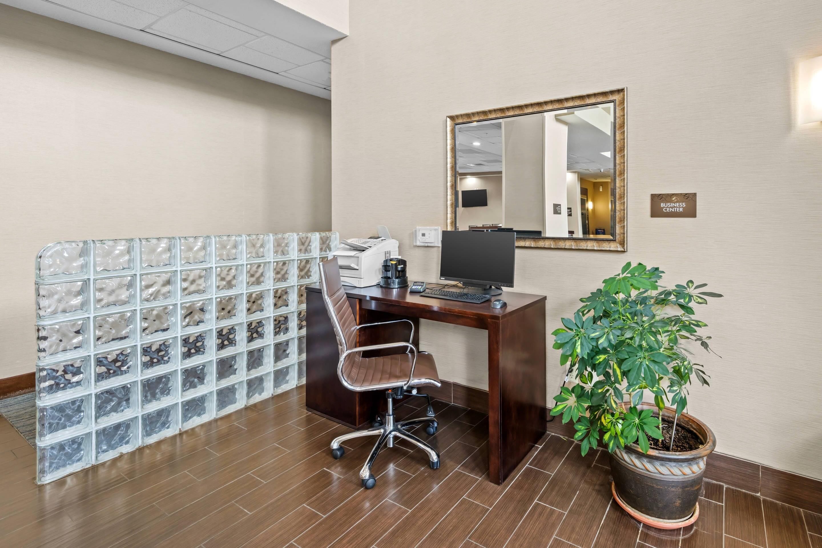 Un espace d’accueil d’hôtel comprenant un comptoir, un ordinateur, une chaise et une plante en pot.