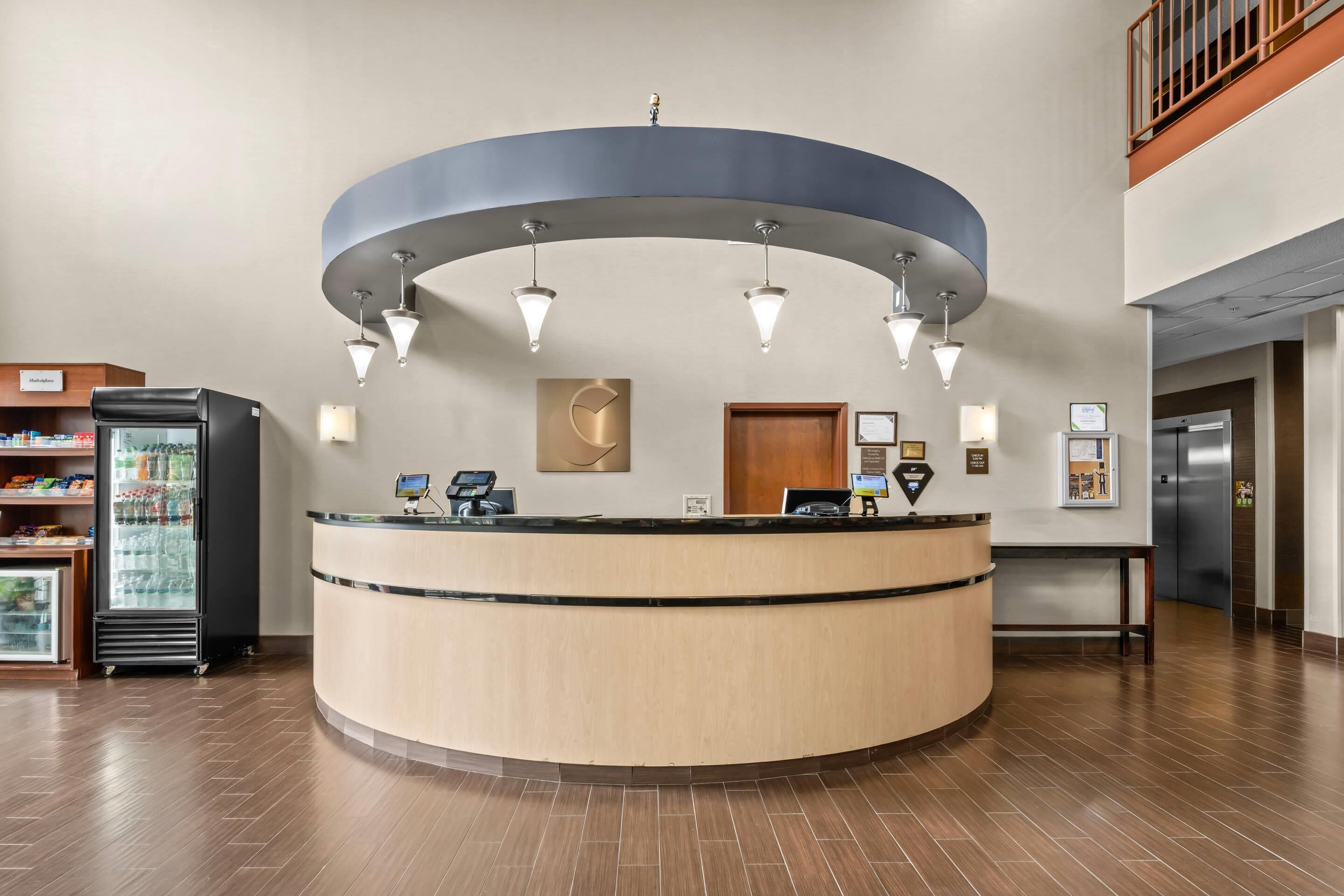 A reception desk with a curved design, a refrigerator, and a wooden door in the background.