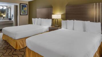 A hotel room with two beds, a large mirror, a painting, and a nightstand with a lamp.