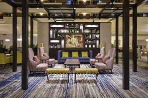 A lobby with a blue sofa, armchairs, a coffee table, and a patterned carpet. - Embassy Suites by Hilton Montgomery Hotel & Conference Ctr (Montgomery)