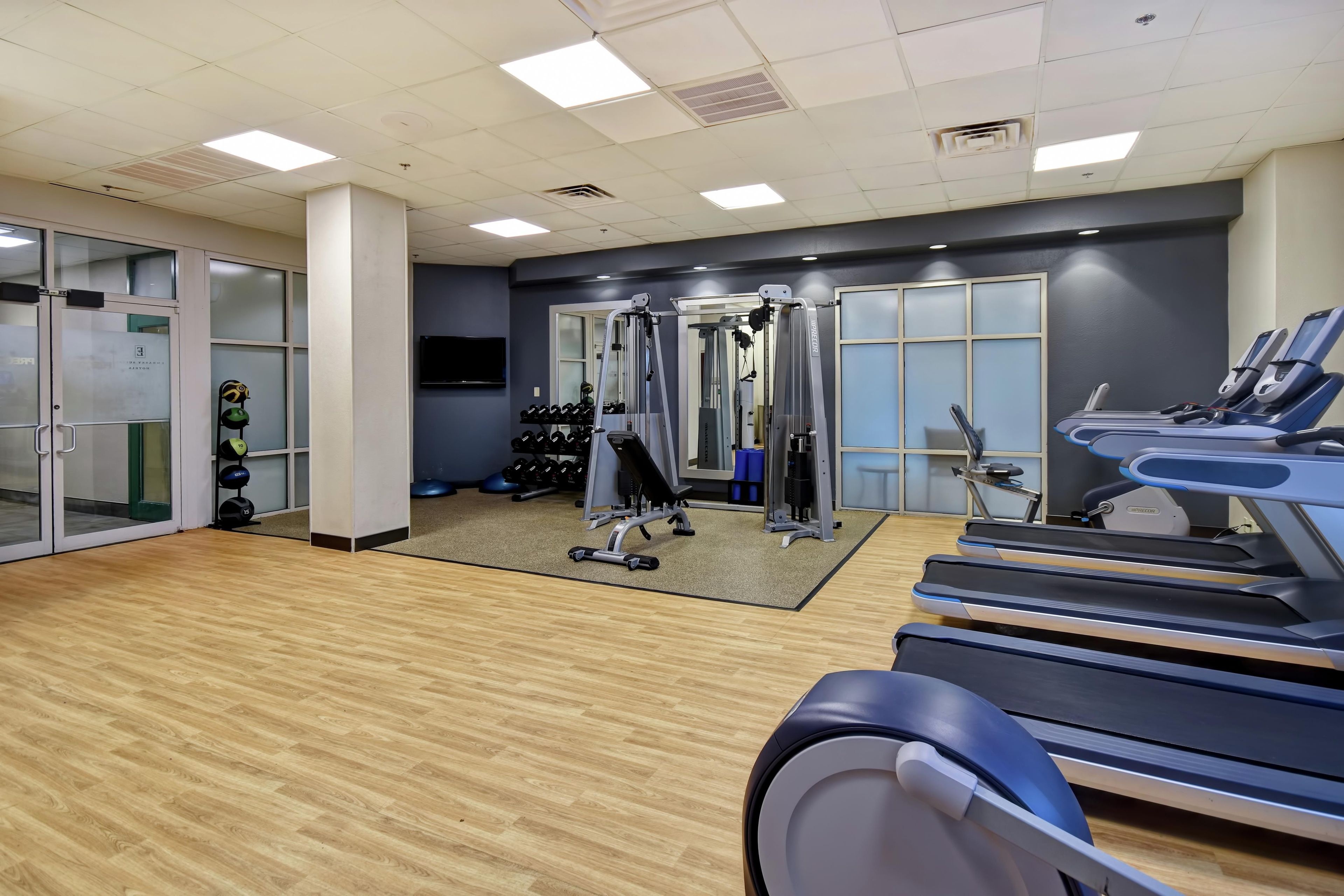Une salle de sport équipée de tapis de course, d’appareils de musculation et d’un miroir.