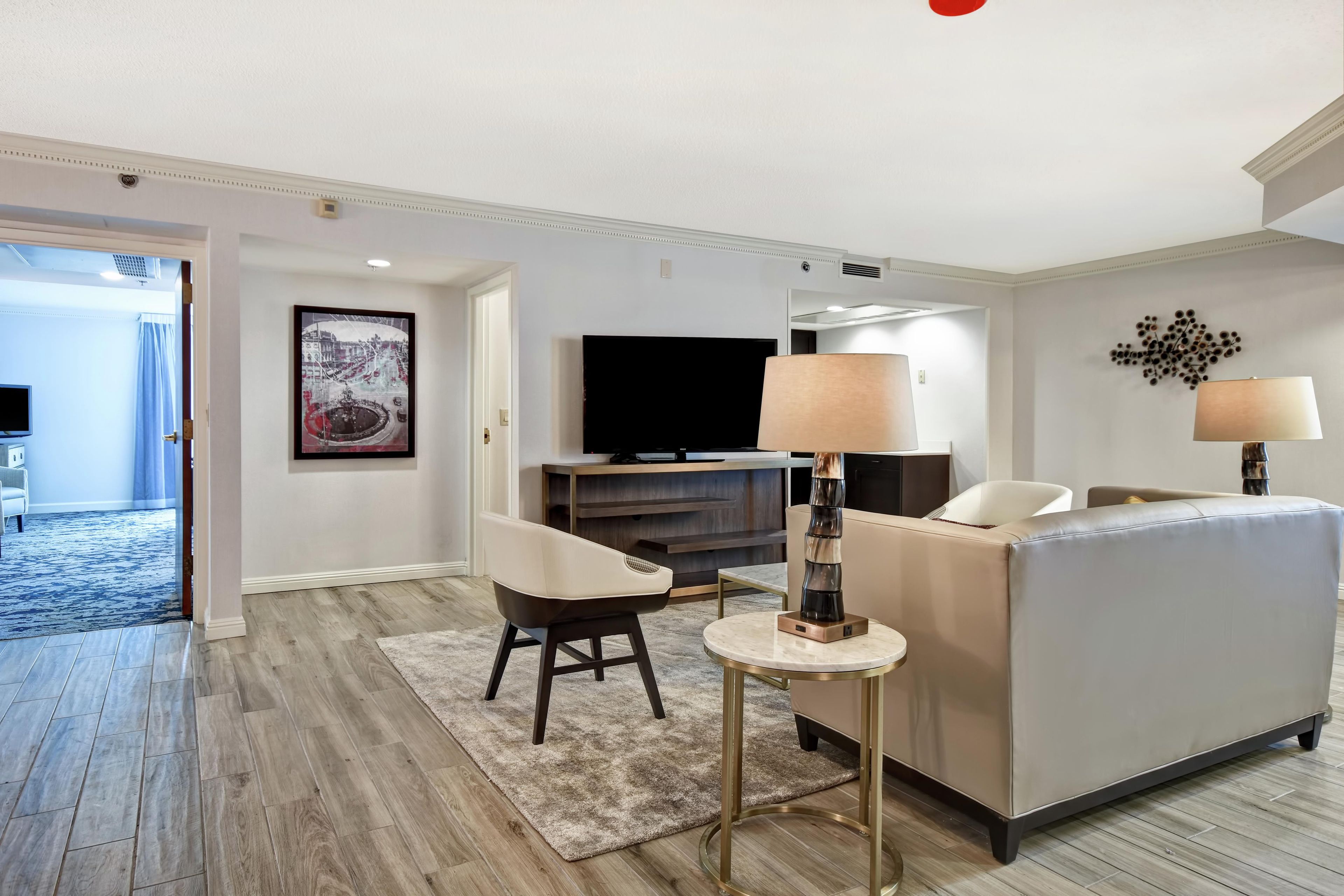 A modern living room with a sofa, a coffee table, a TV, and a painting on the wall.