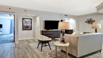 A modern living room with a sofa, a coffee table, a TV, and a painting on the wall.