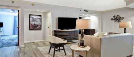 A modern living room with a sofa, a coffee table, a TV, and a painting on the wall.