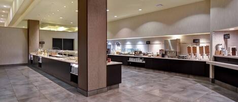A modern hotel kitchen with a central island, buffet area, and a coffee station.