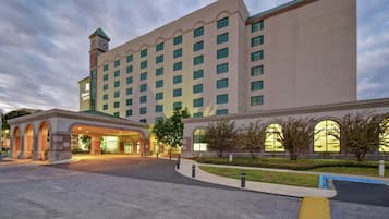 A large hotel with multiple floors, a prominent clock tower, and a well-lit entrance.